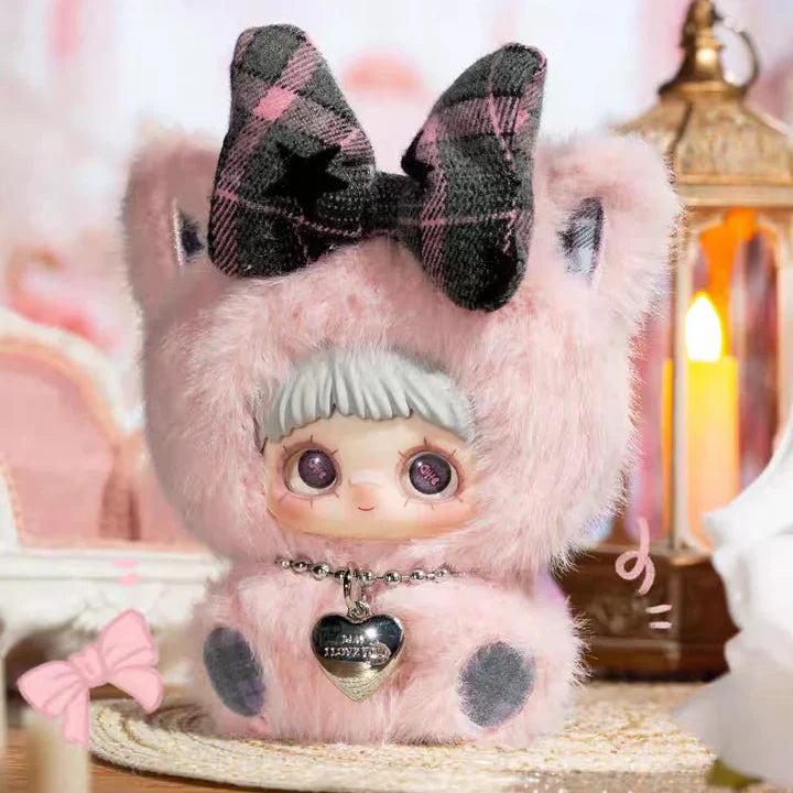 Toy figure with pink fur and plaid bow, 'First Love' text on a blurred background